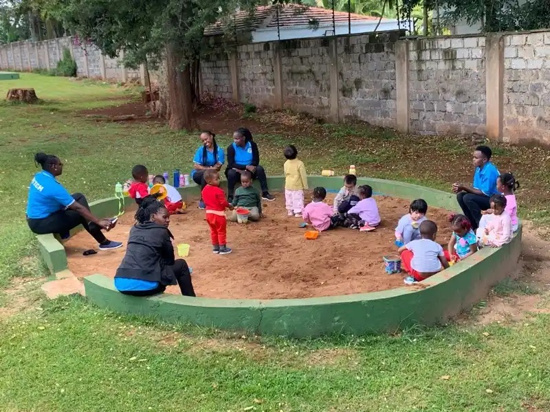 Children and teachers playing in the sandbox