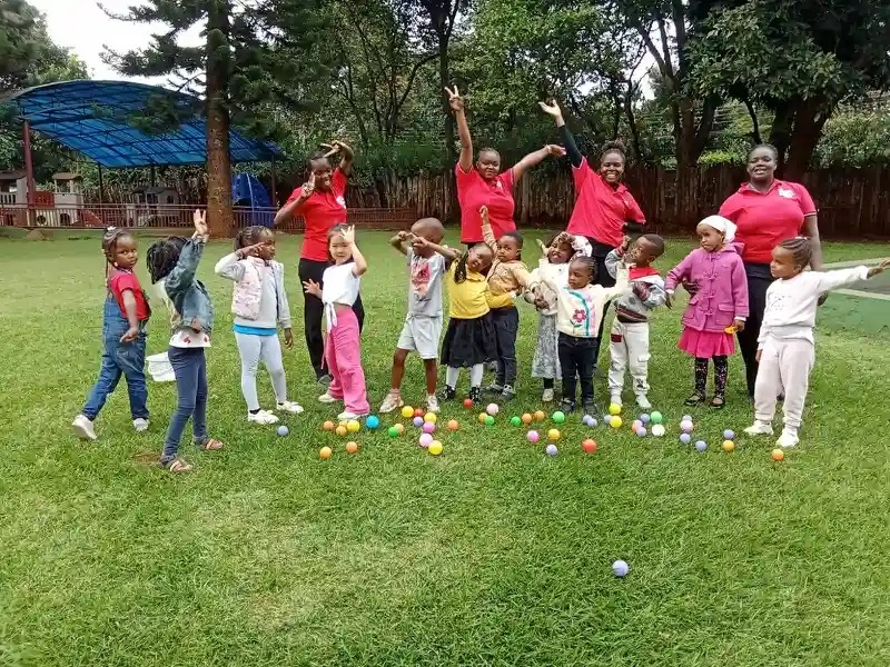 Playgroup children playing with coloured balls outdoors