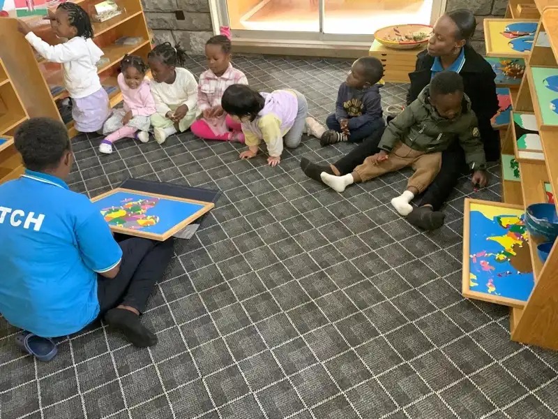 Pre-Nursery children working on map puzzles with their teacher
