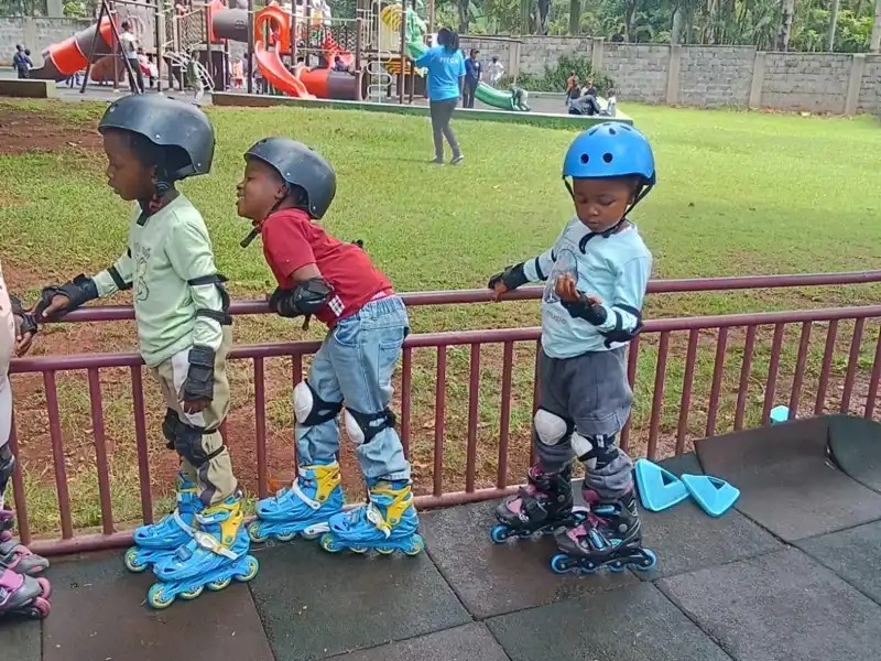 Children roller skating in a line outdoors