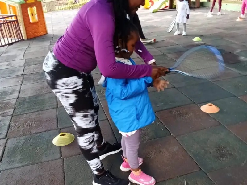 Teacher helping a child learn badminton