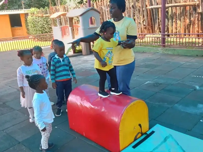 Children practising on a gym vault with teacher support