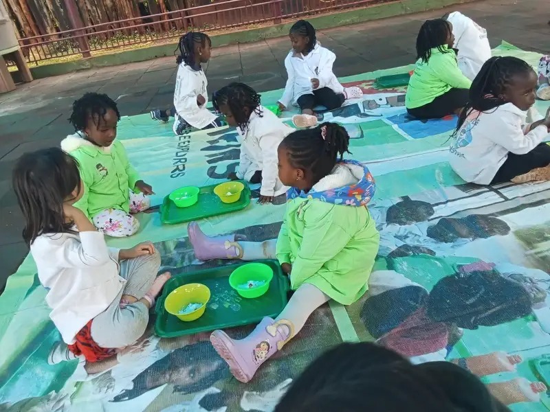 Children exploring sensory trays on a mat