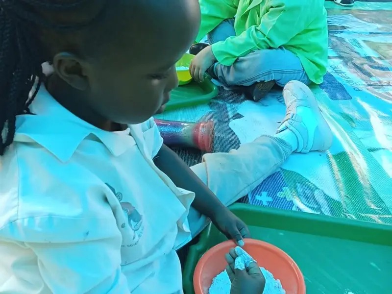 A child's hands exploring blue sand